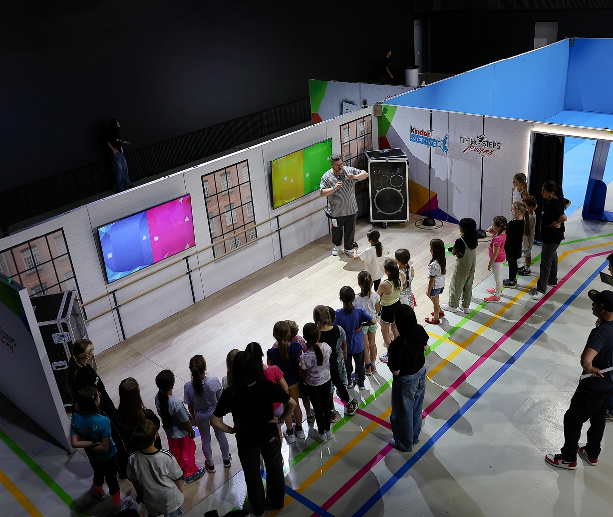 Der interaktive-Eventparcours von oben: Kinder stehen im Halbkreis um einen Showmaster, der eine Enführung gibt.
