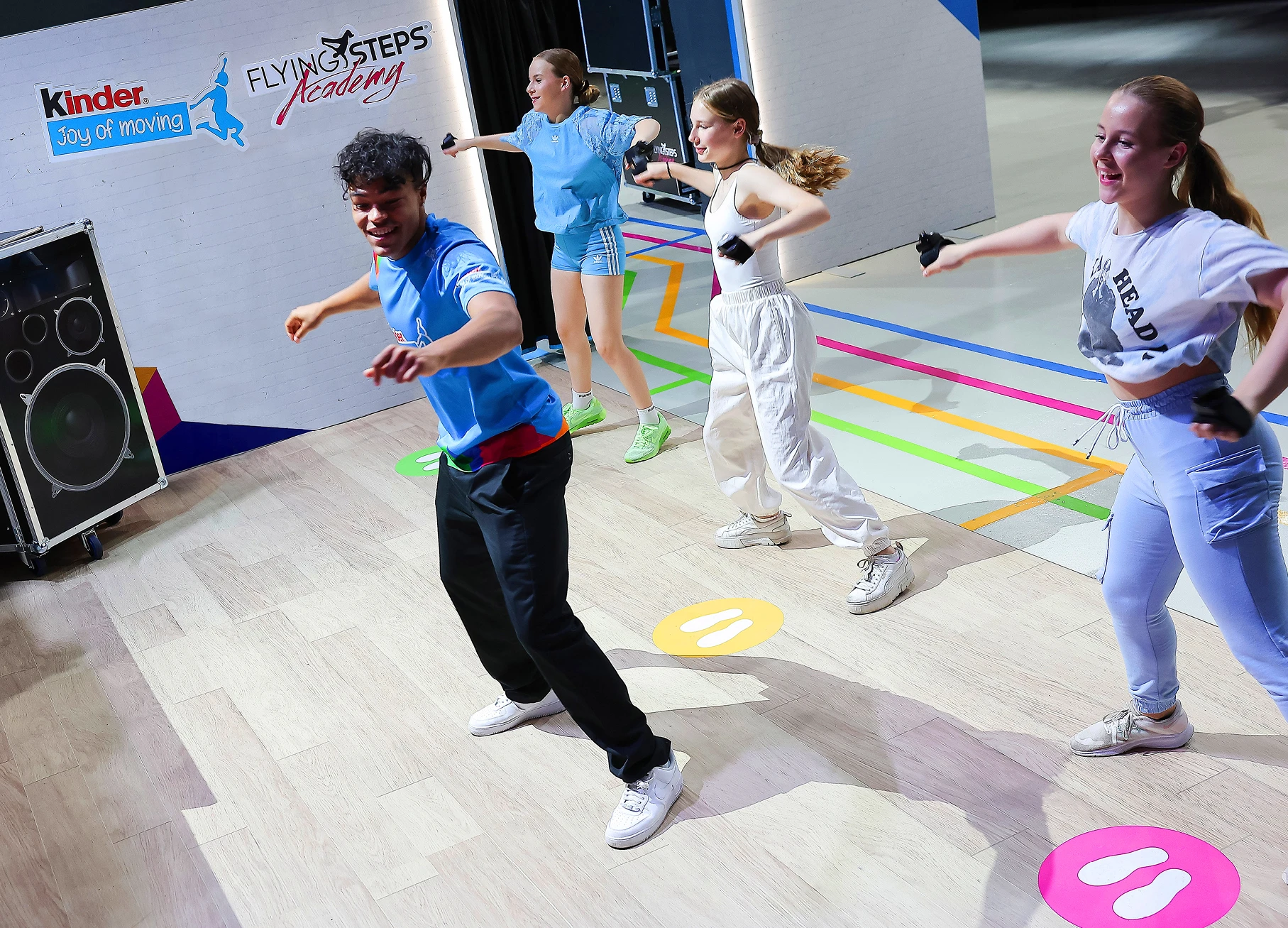 Flying Steps Marke Erlebnis Preussisch Portugal Zwei Markenbotschafter / Influencer lehnen auf einem Spieltisch. Große Arcade-Buttons sind in die Oberfläche integriert um das Rhytmusgefühl der Kinder zu testen.