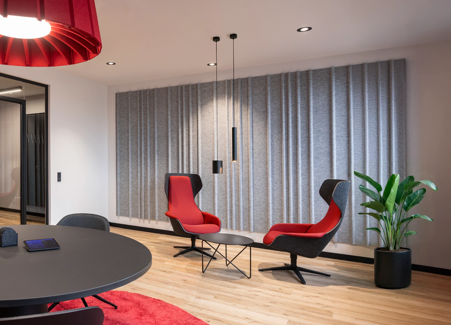 Office-Konzept: umgestalteter Konferenzraum mit akustisch wirksamen Materialien, bequemen Besprechungssesseln und grüner Pflanze