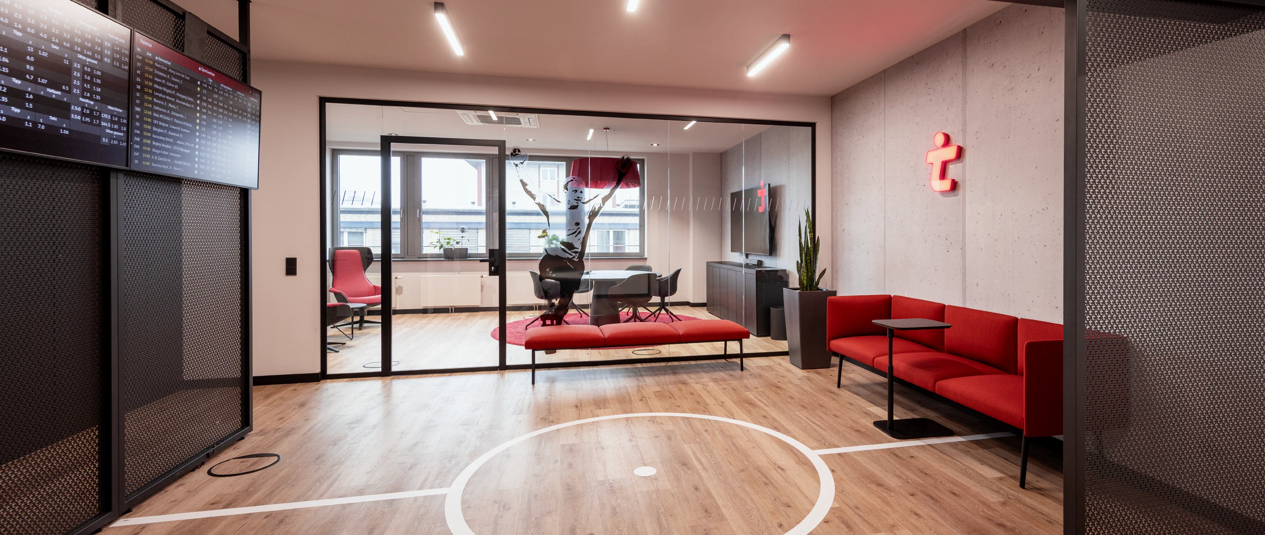 Office-Konzept: Blick in einen modernen Konferenzraum, mit Betonwand und Neon-Logo und Soft Work Sofa, Grafische Folierung auf dem Boden